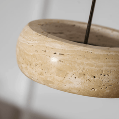 Ronde travertijn hanglamp in donutvorm aan een zwarte metalen stang