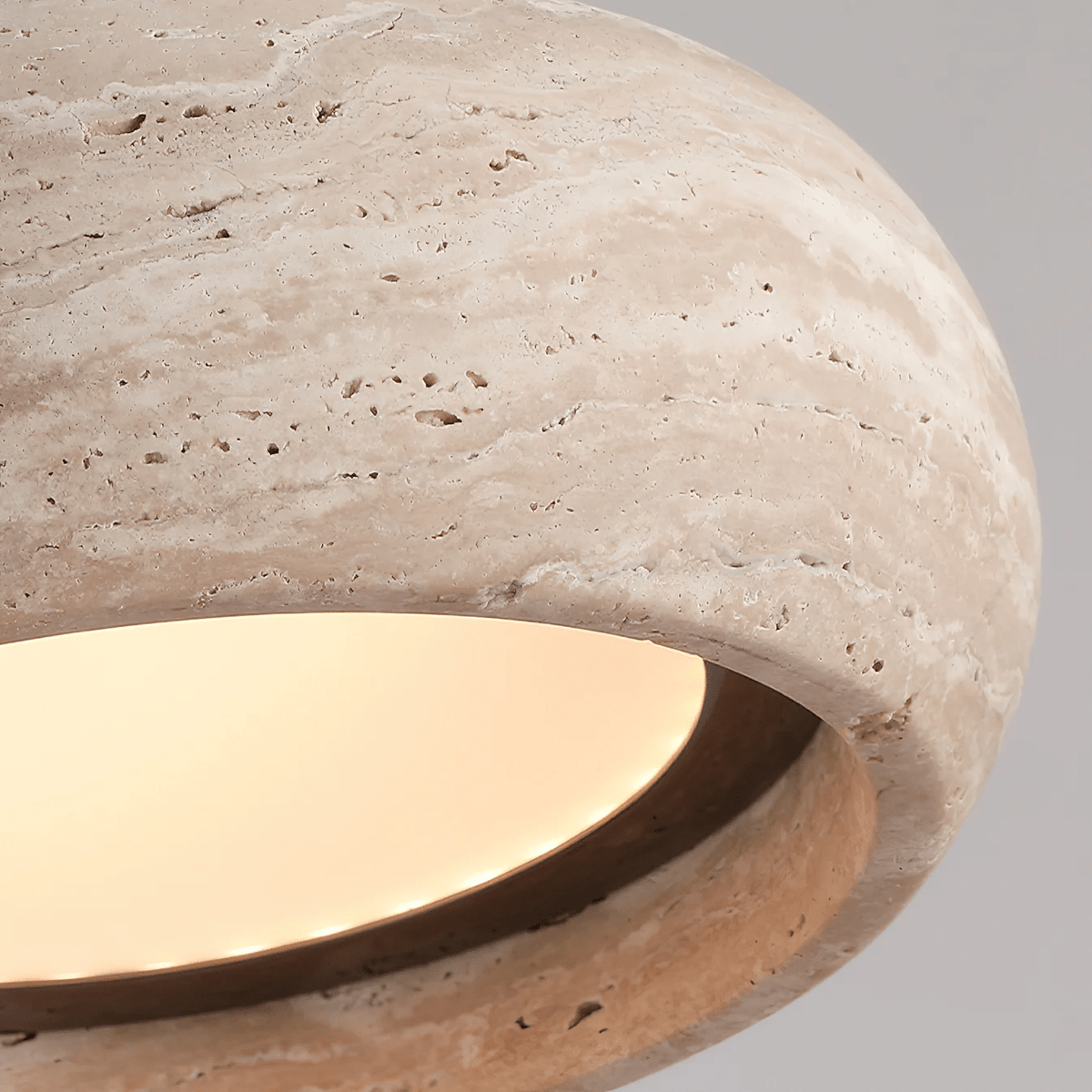 Ronde travertijn hanglamp in donutvorm aan een zwarte metalen stang