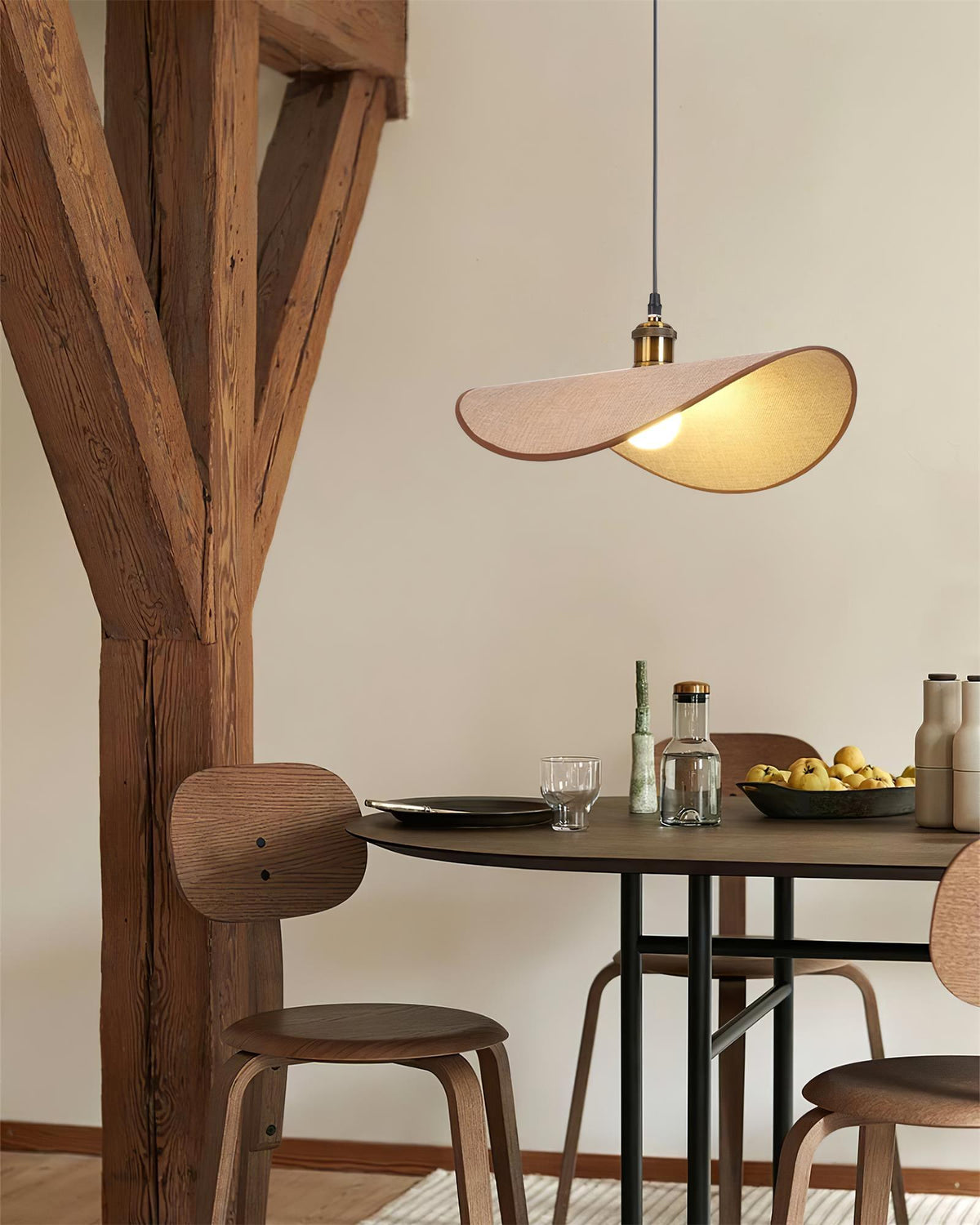 Hanglamp met ronde linnen kap en houten accenten boven een eettafel