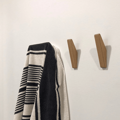 Tweekleurige houten wandhaken naast elkaar aan de muur