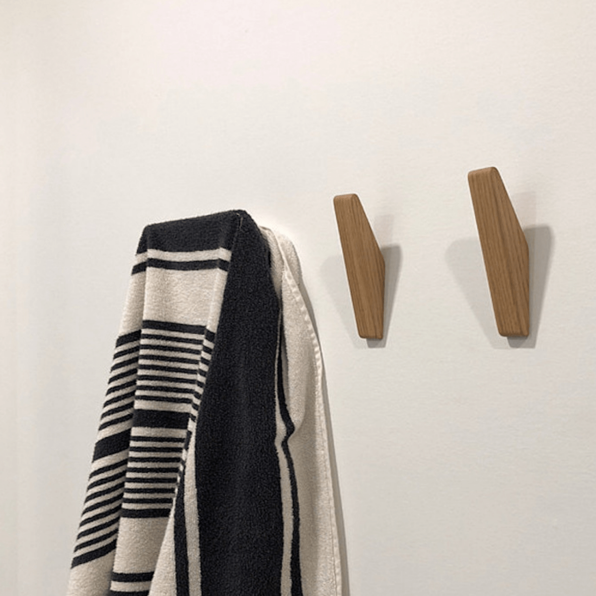 Tweekleurige houten wandhaken naast elkaar aan de muur